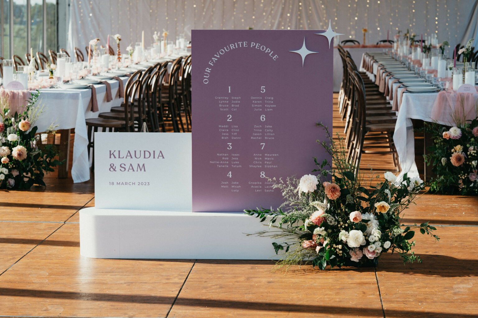White welcome sign and purple seating chart at a wedding