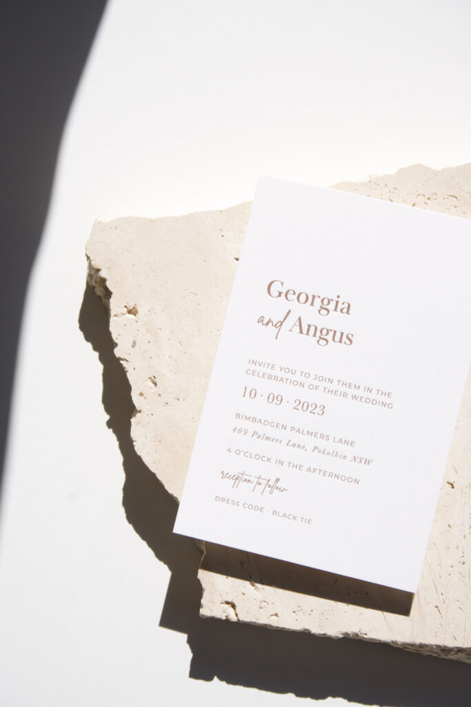 White eco-friendly wedding invitation designed with minimal ink placed on top of a travertine stone.