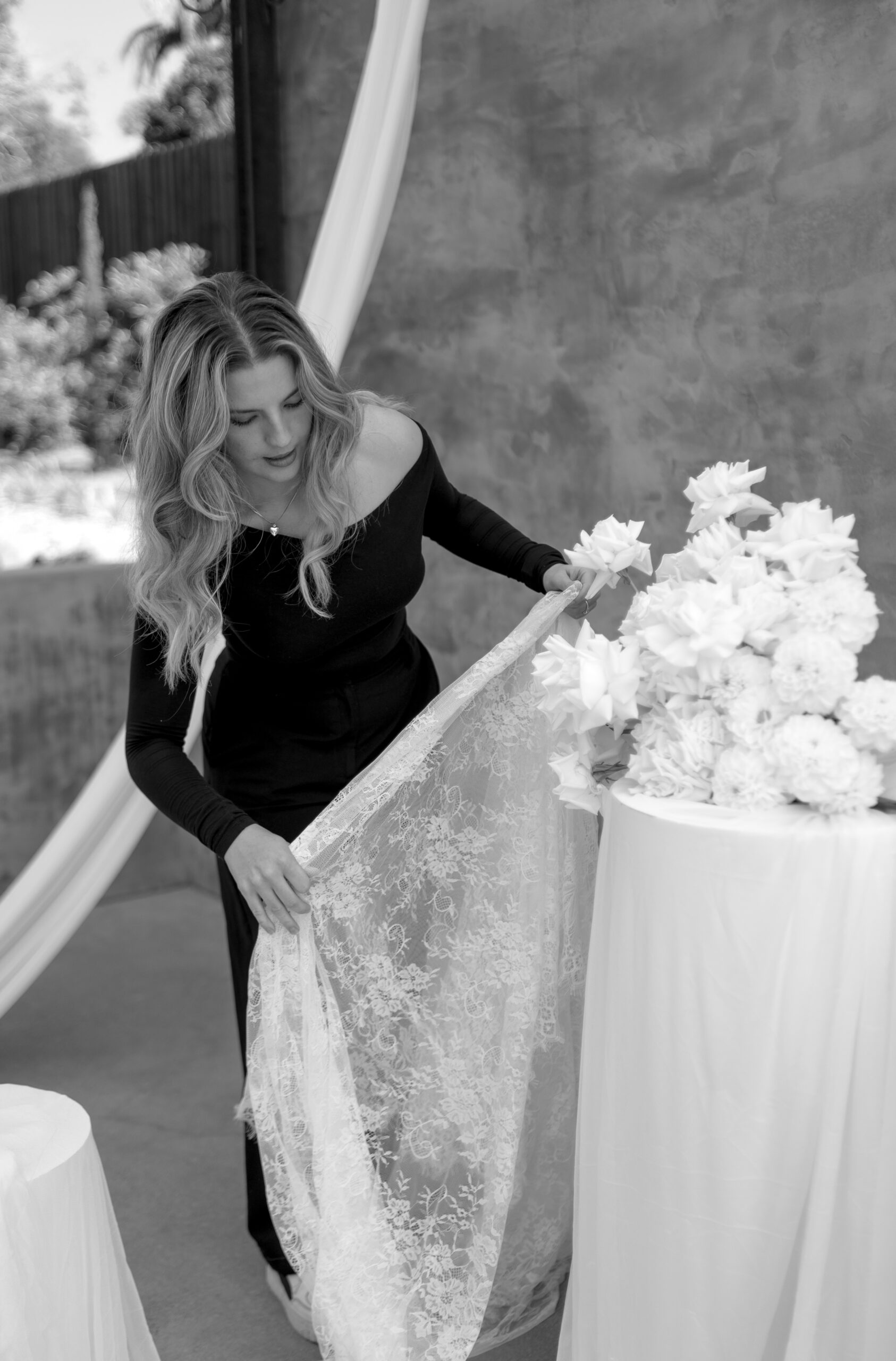 Rayna from Vows & Things adjusting fabric around a table holding a floral arrangement