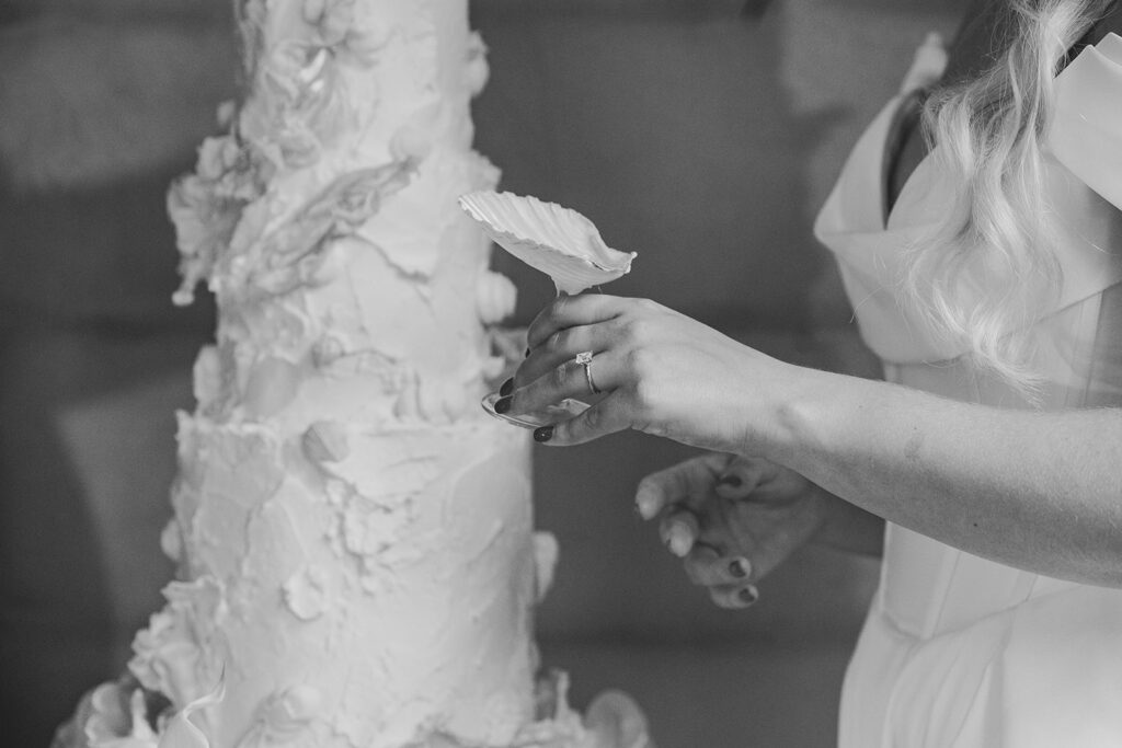 Hand placing a floral piece onto a wedding cake.
