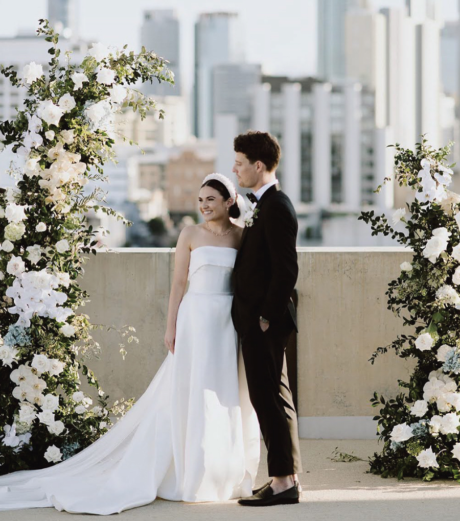 Bride and Groom standing between two floral arrangements